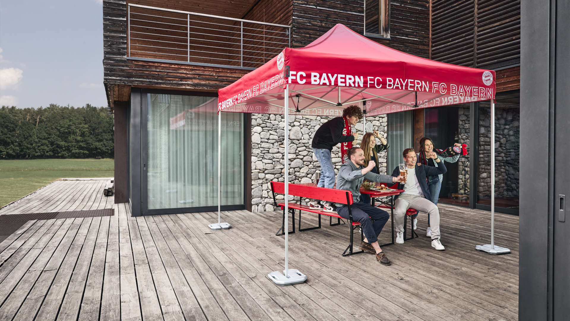 Fans  jubeln beim Fußball schauen auf der Terrasse unter dem FC Bayern München Faltpavillon