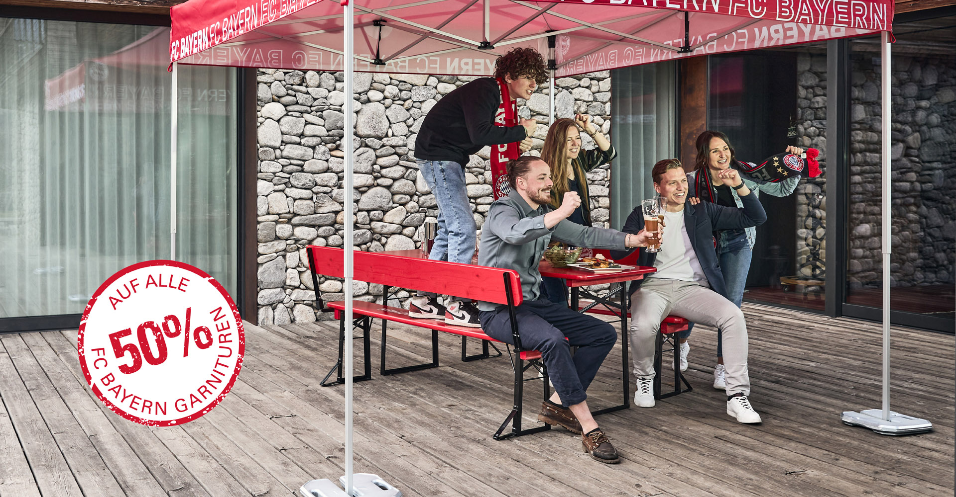Fünf Personen feuern ihre Lieblings-Fußballmannschaft an - auf einer Bierzeltgarnitur und unter einem Faltpavillon im FC Bayern München Stil.
